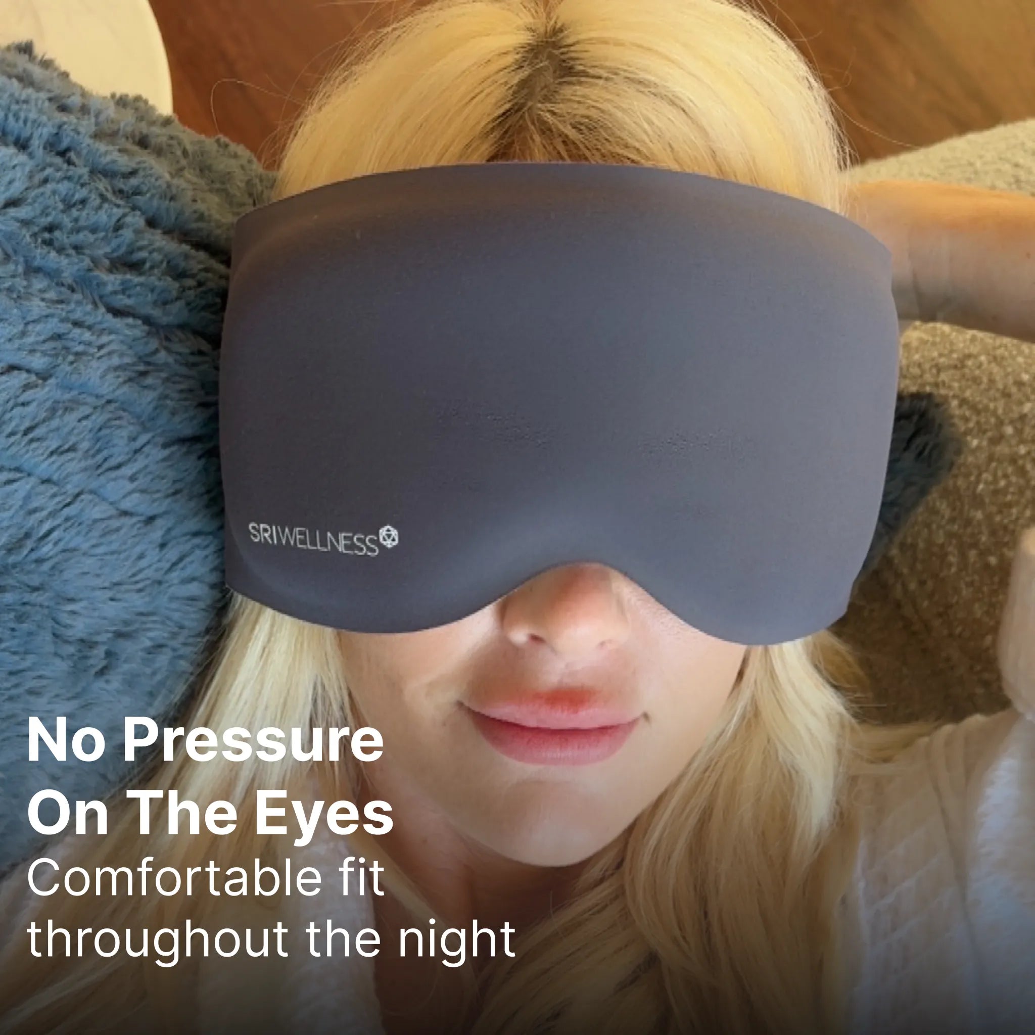 A close-up of a person lying down wearing a dark gray eye mask, with text on the left reading 'No Pressure On The Eyes Comfortable fit throughout the night'. The mask has the brand name 'SRIVELLNESS' printed on it.